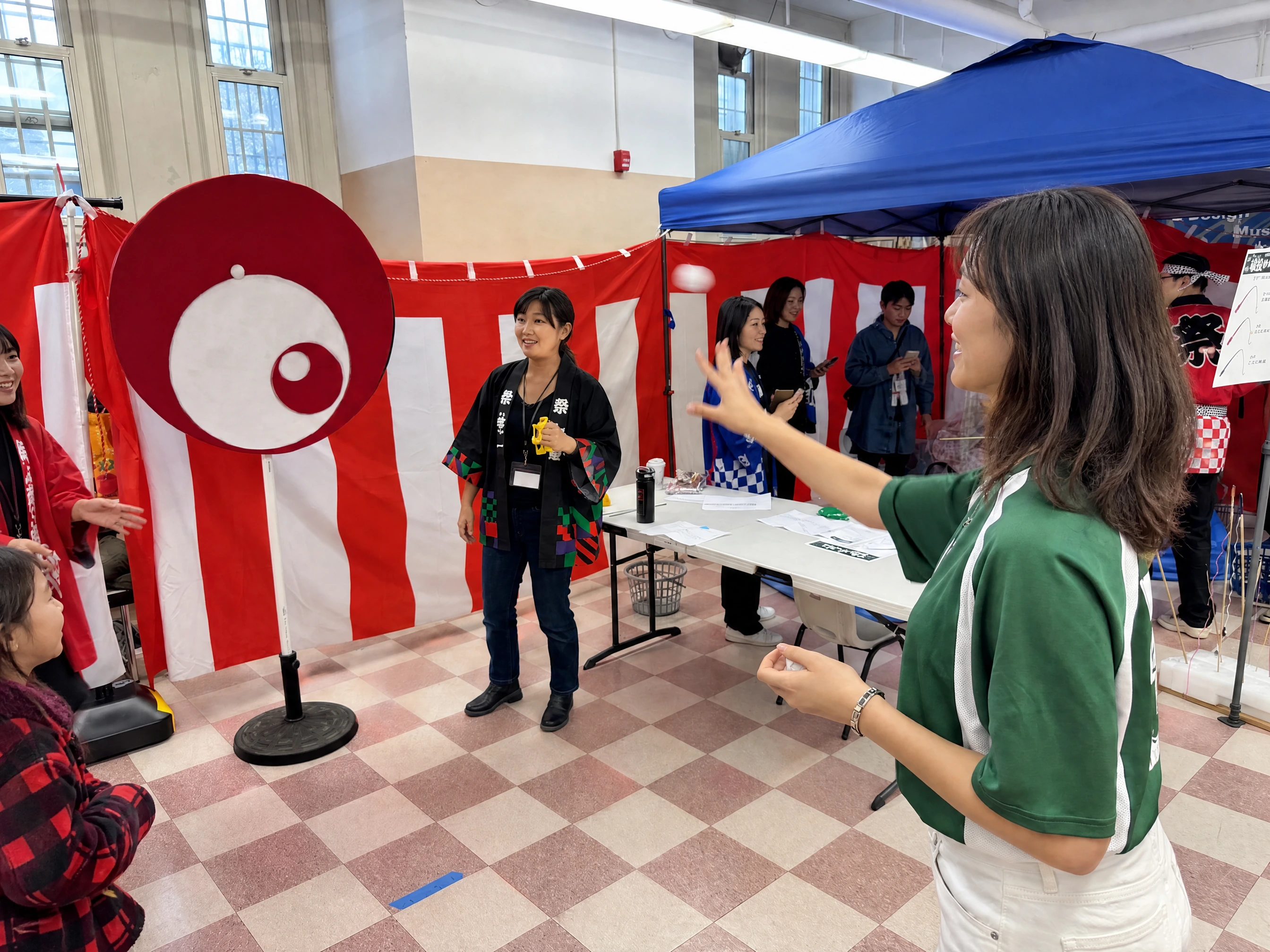 A player throwing at the spinning eye target while a volunteer in branded happi watches
