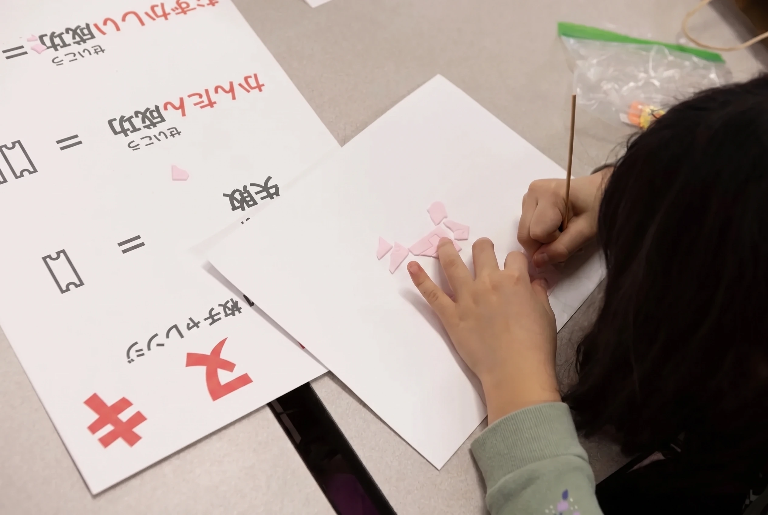 A child carving a pink katanuki tablet with a needle beside the reward card for easy success, hard success and failure